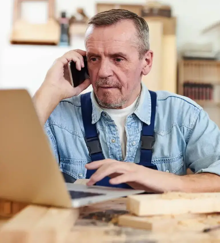 A man takes a break from carpentry work to discuss his business plans over the phone.