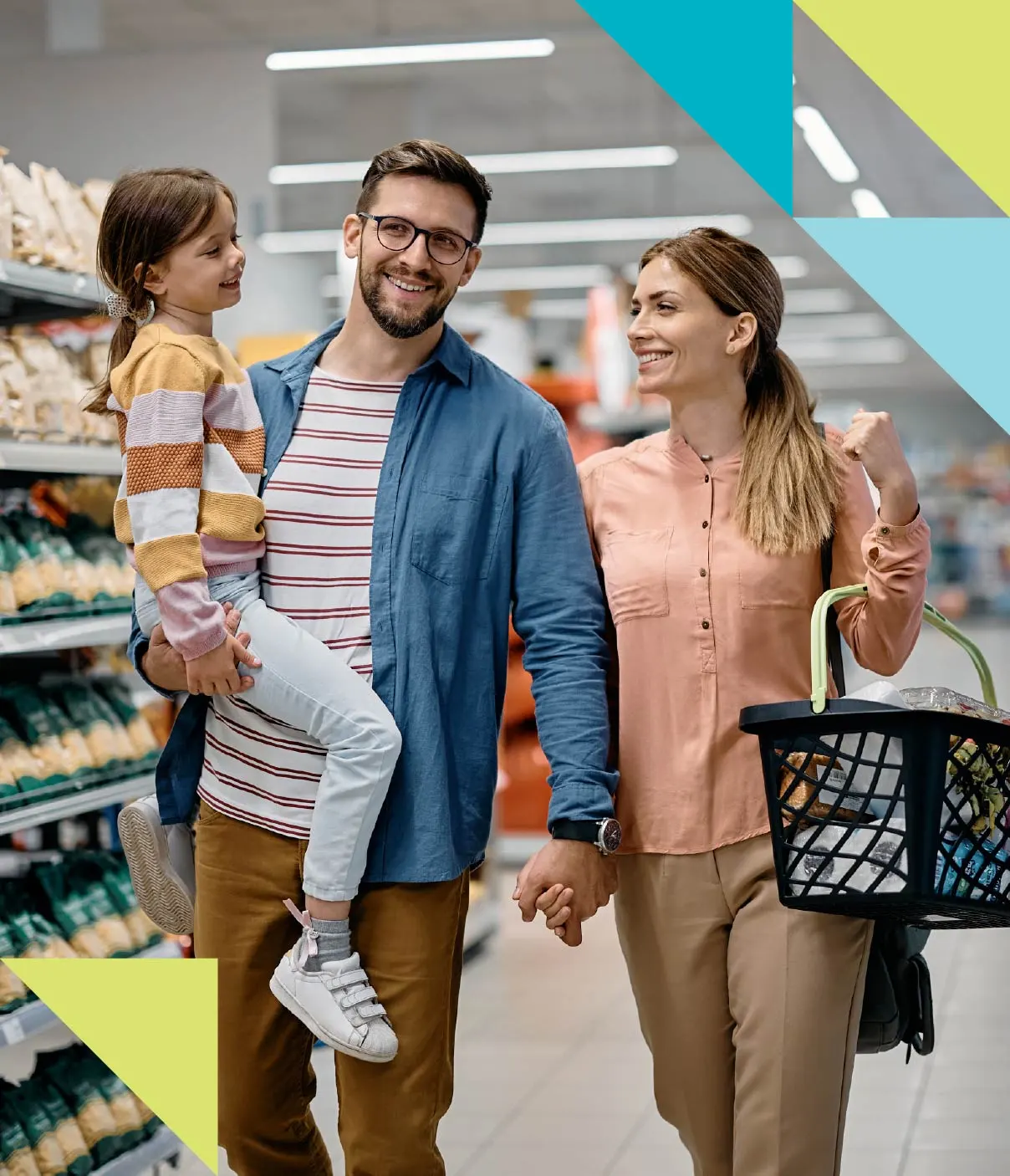 A man carries his daughter and holds his wife’s hand while they grocery shop together.