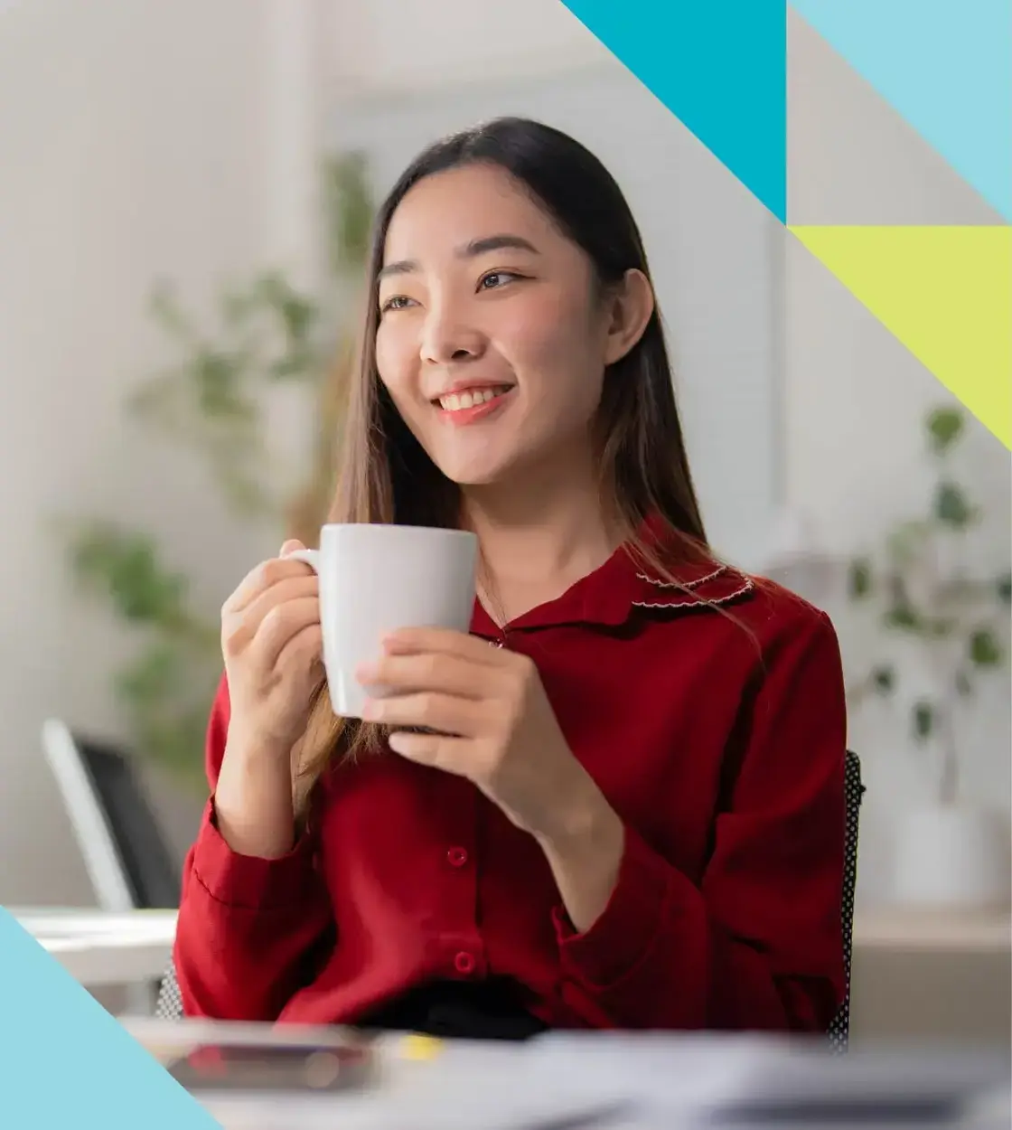 A young woman in a red blouse smiles off camera while holding a cup of coffee.