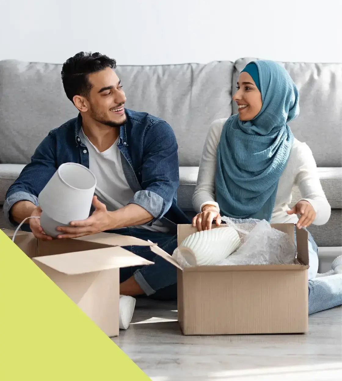A pair of new homeowners trade smiles as they unpack home décor items.