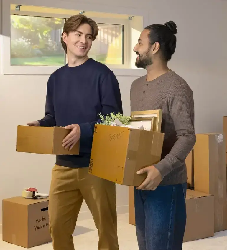Two young men engage in conversation while they pack up some moving boxes.