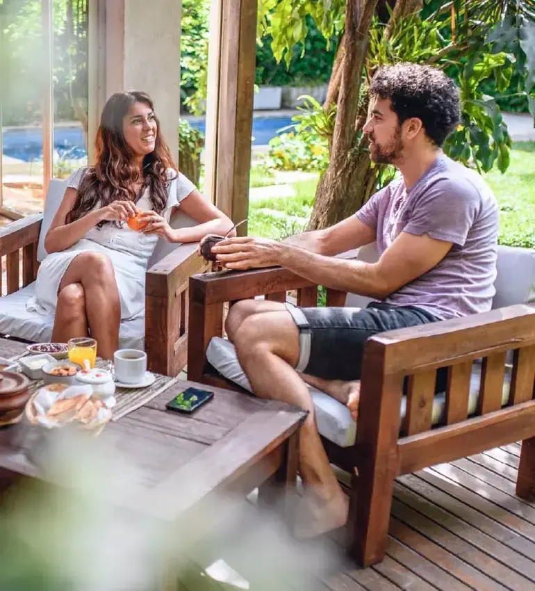 A man and woman take time to savour the summer sun over breakfast on a backyard patio.