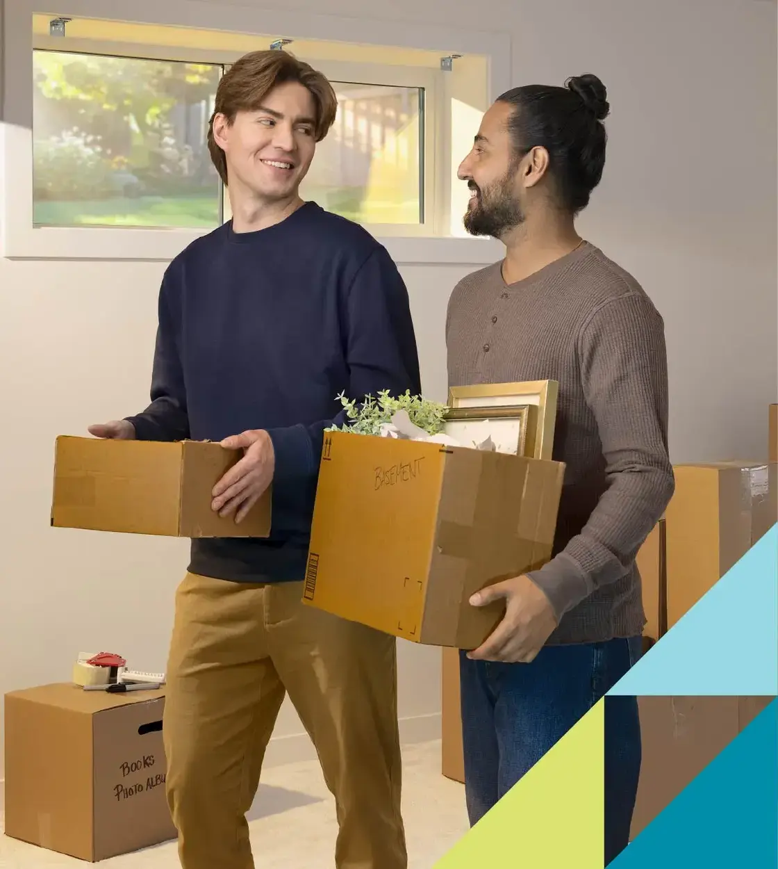 Two young men engage in conversation while they pack up some moving boxes.