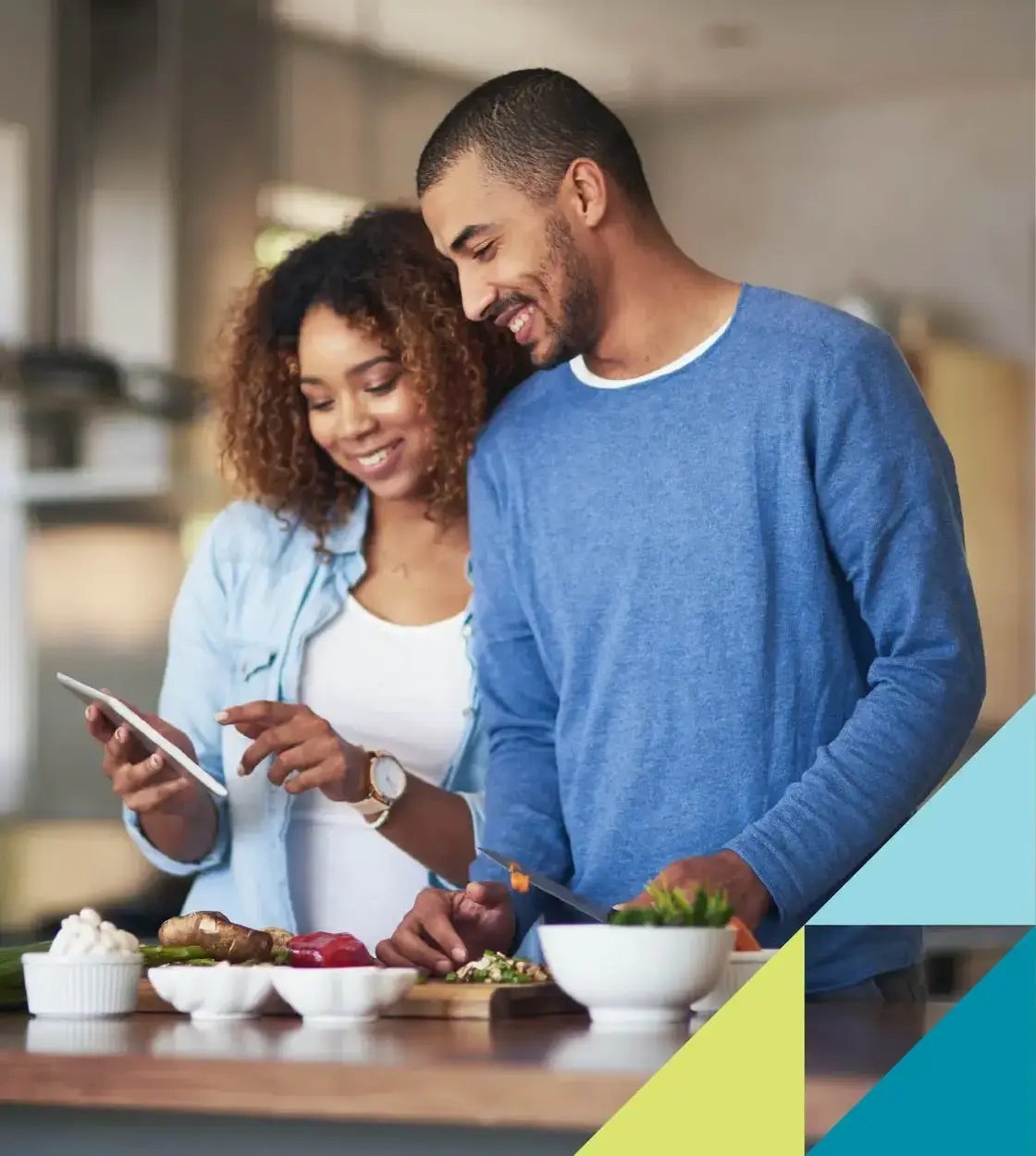 A man and woman prepare a meal at home by following an online recipe via mobile phone. 