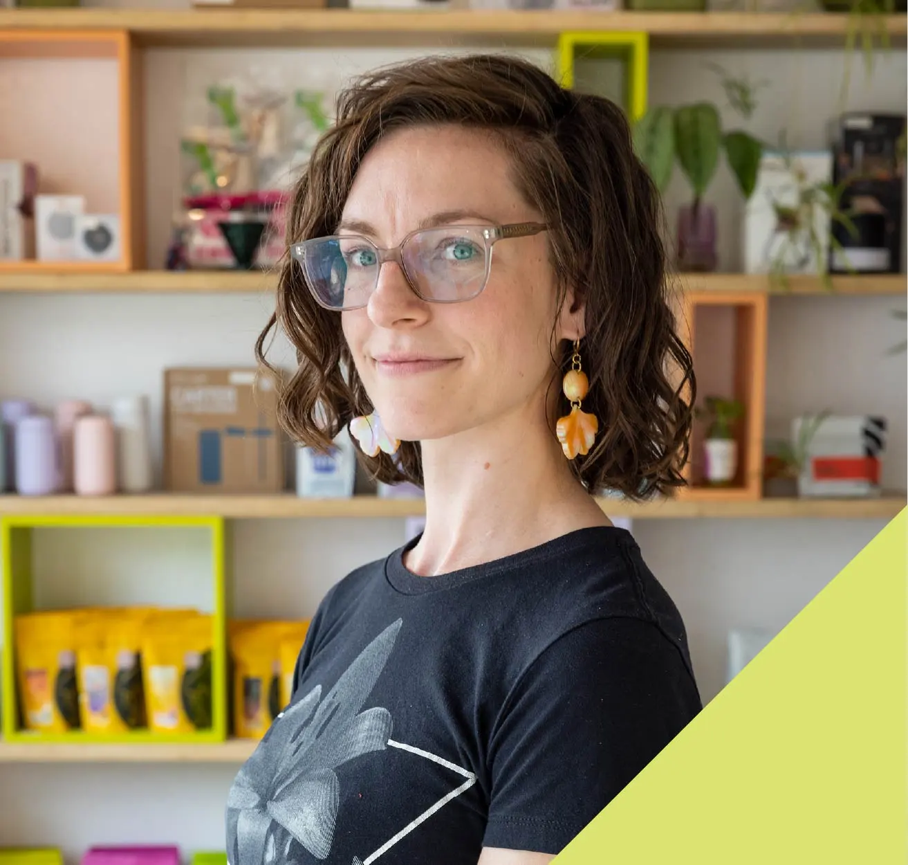 A woman in glasses and printed t-shirt looks at the camera.