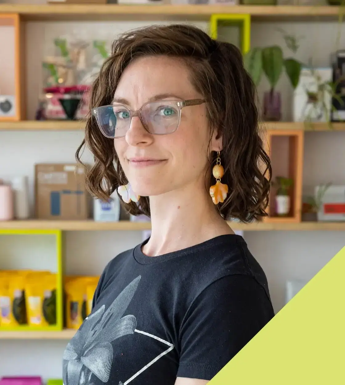 A woman in glasses and printed t-shirt looks at the camera.