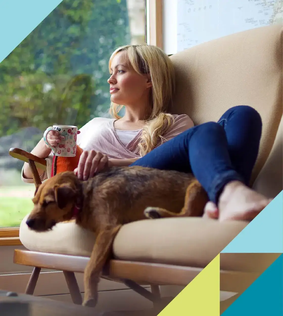 A young blonde woman cuddles up with her sleepy pup on the couch over a warm cup of coffee.