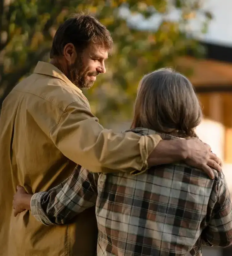 A man and woman dressed in fall clothing put their arms around each other.