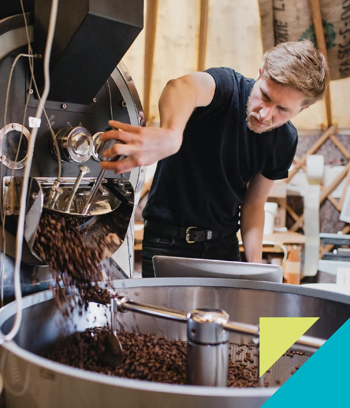 A young man with blonde hair in a black t-shirt prepares coffee beans.