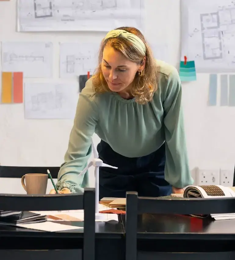 A busy female professional sketches some layout designs on a black kitchen table.
