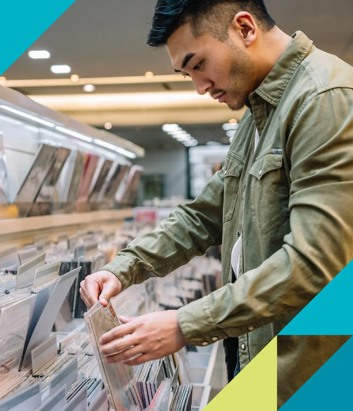 A young man wearing a beige denim jacket flips through a selection of vinyl records.