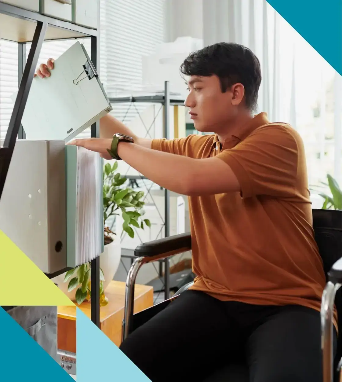 A young man seated in a bright living room organizes his work shelf.