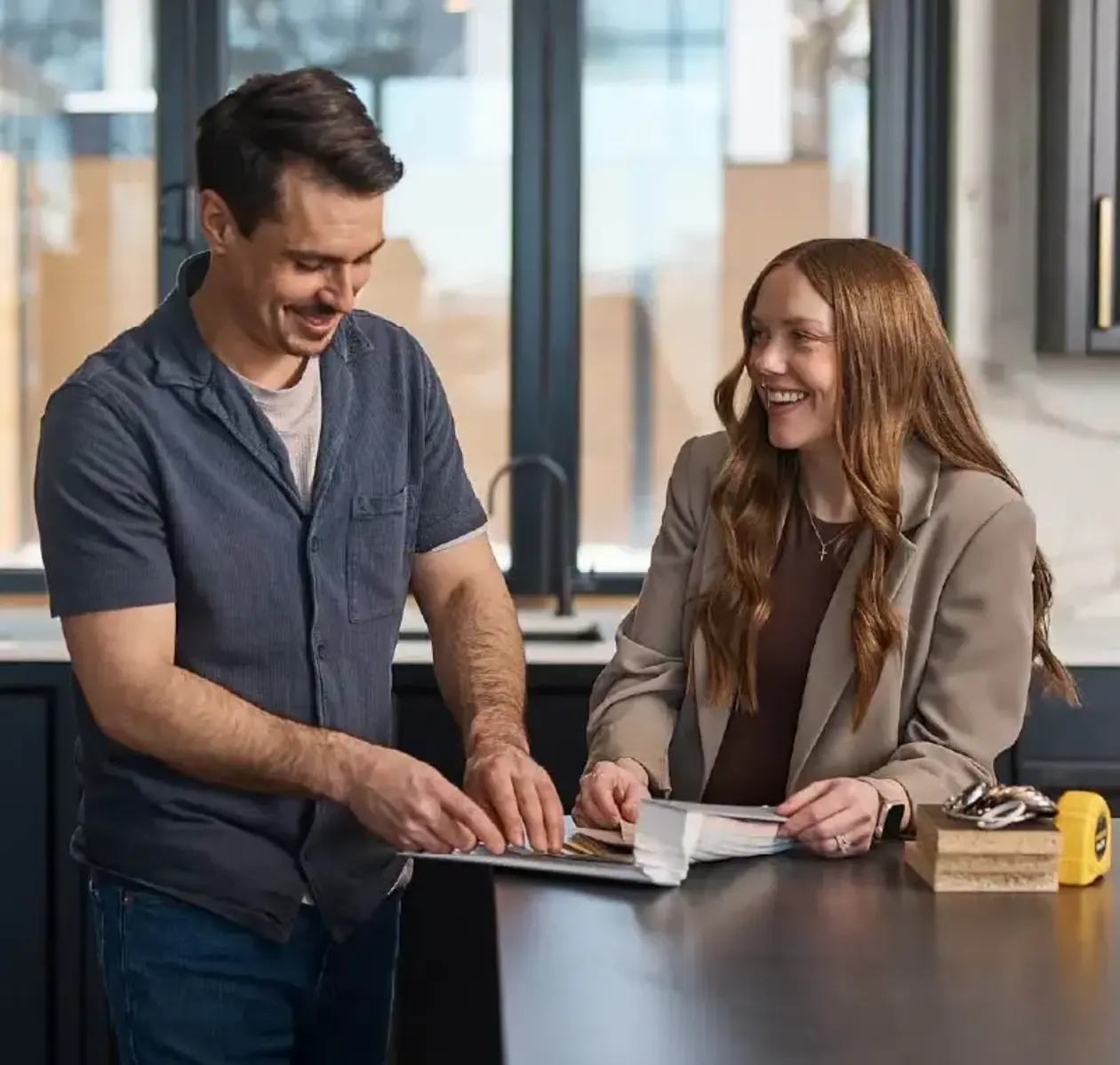 A man and woman excitedly explore colour options inside a new home build.