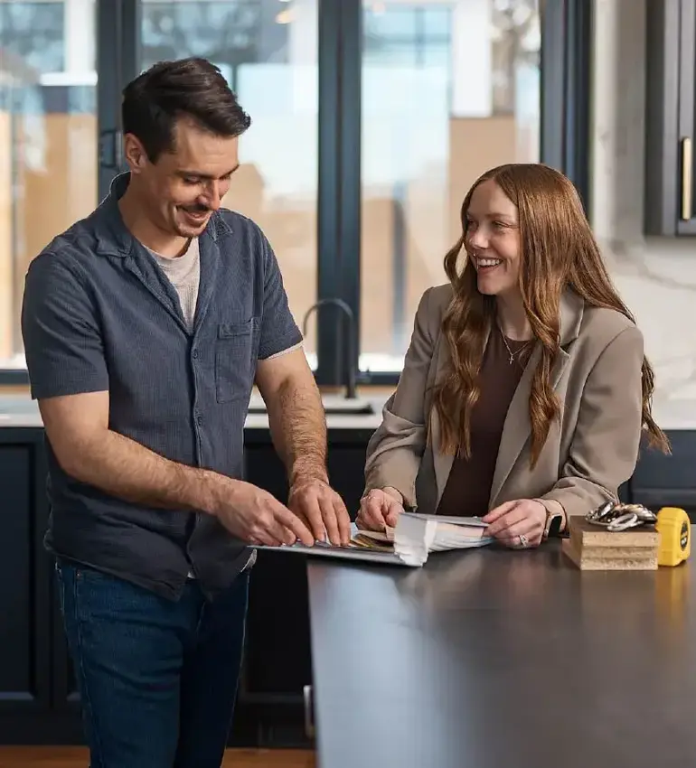 A man and woman excitedly explore colour options inside a new home build.