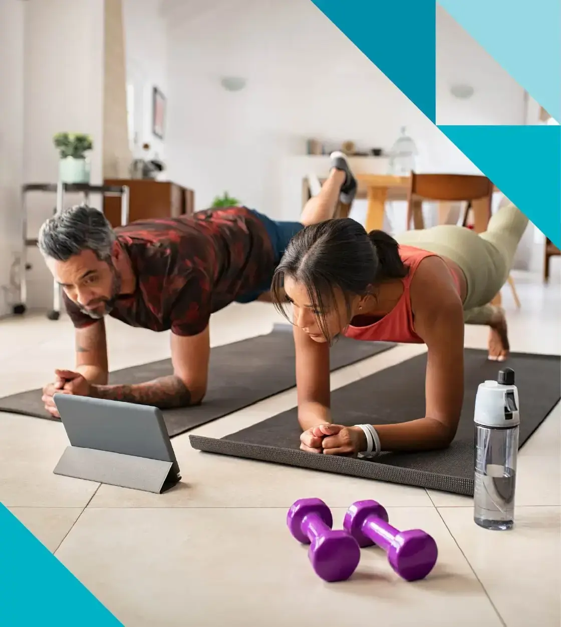 A couple keeps fit in their kitchen as they follow a workout video on their tablet.