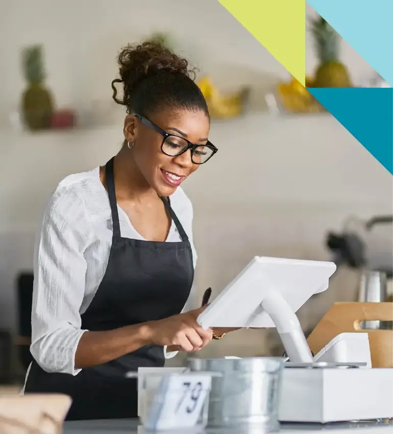 A woman wearing glasses and an apron enters an order into her work’s point of sale system.