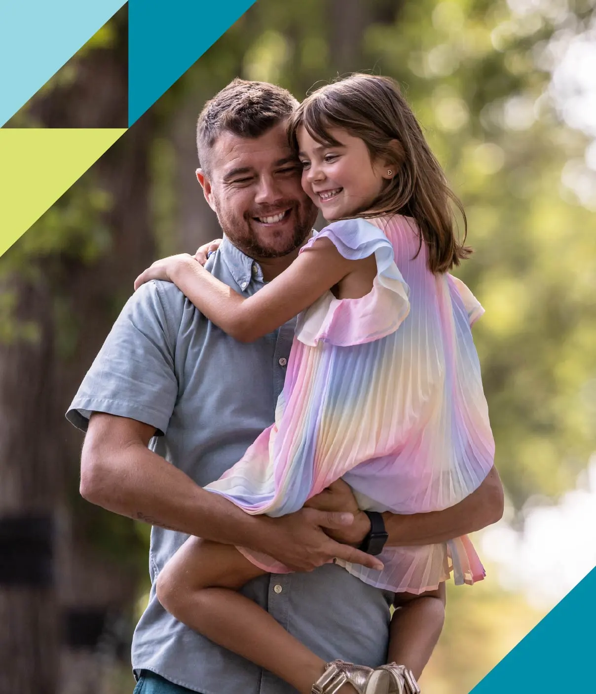 A young father smiles as he carries his happy daughter clad in a rainbow-coloured dress.