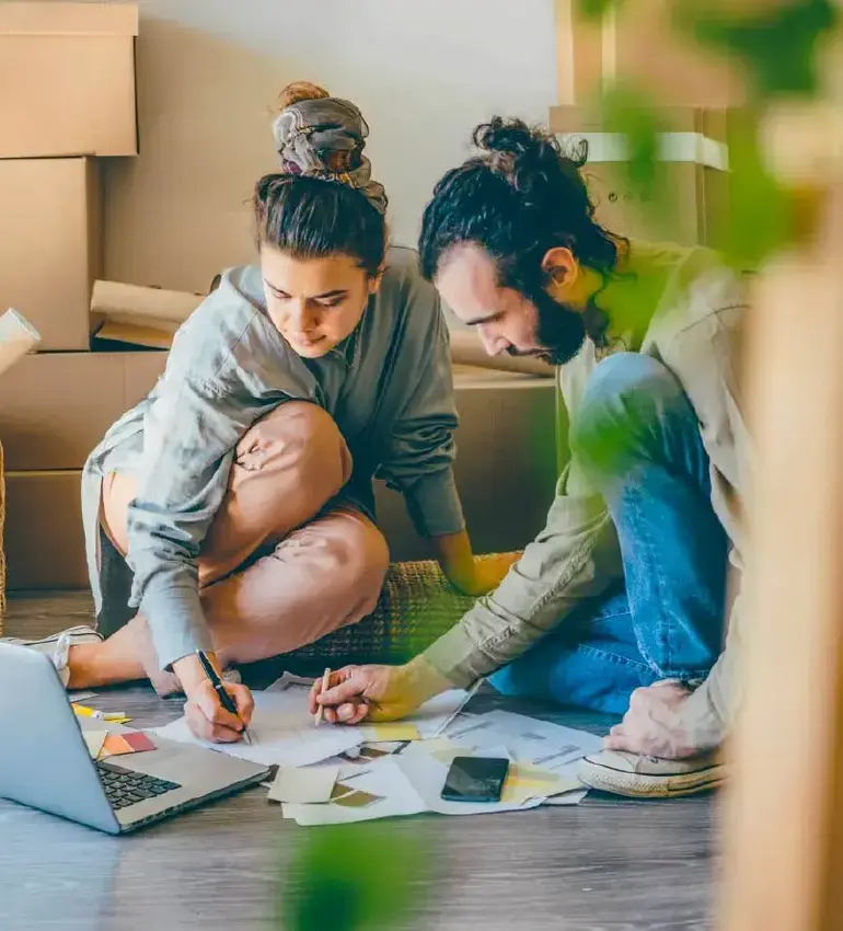 Surrounded by moving boxes, a young couple mockup the perfect layout plan for their new home.
