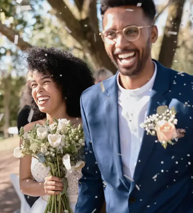 A pair of newlyweds are showered in confetti upon the conclusion of an outdoor wedding ceremony.