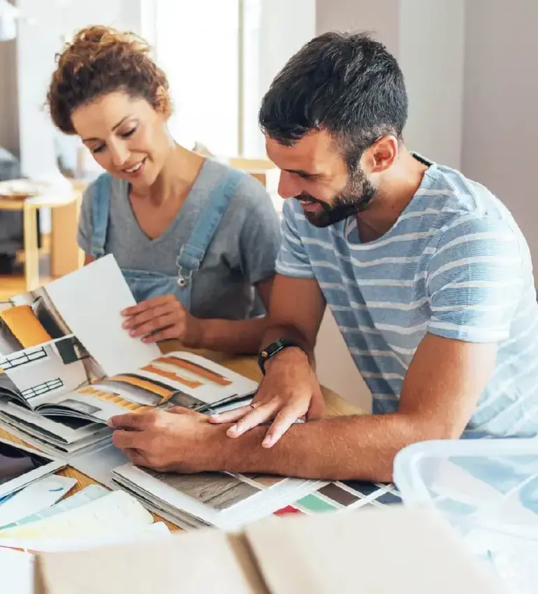 A man and woman explore interior design options on a kitchen table.
