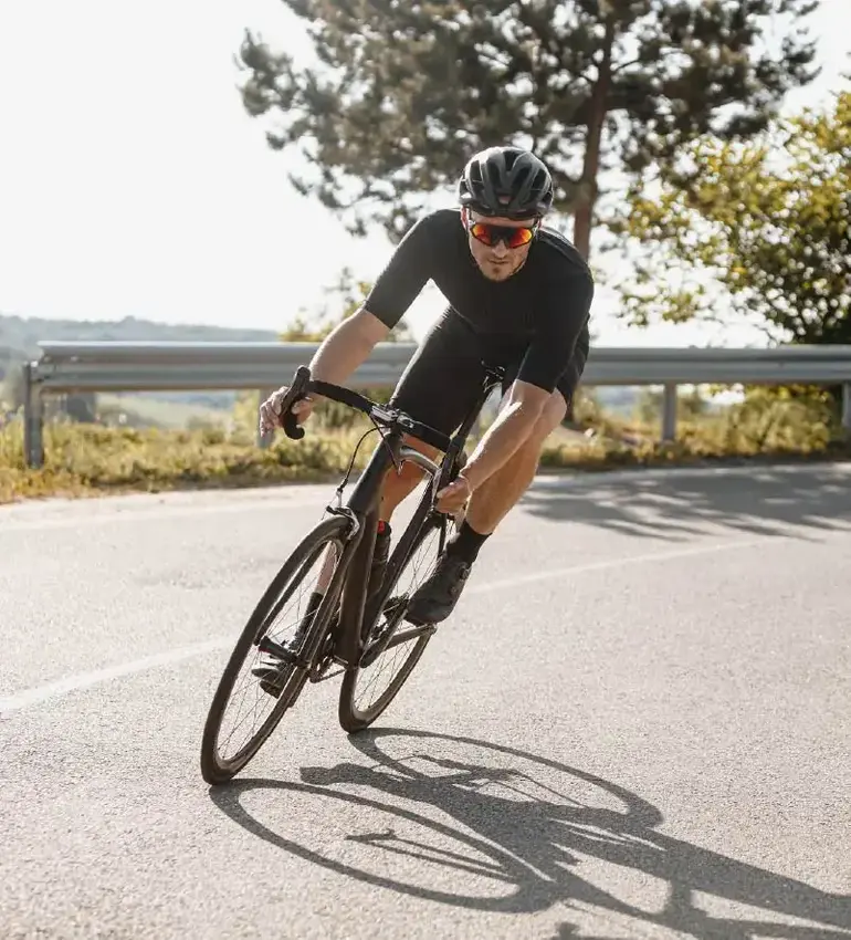 A male cyclist rounds a corner on his ride along a country road.