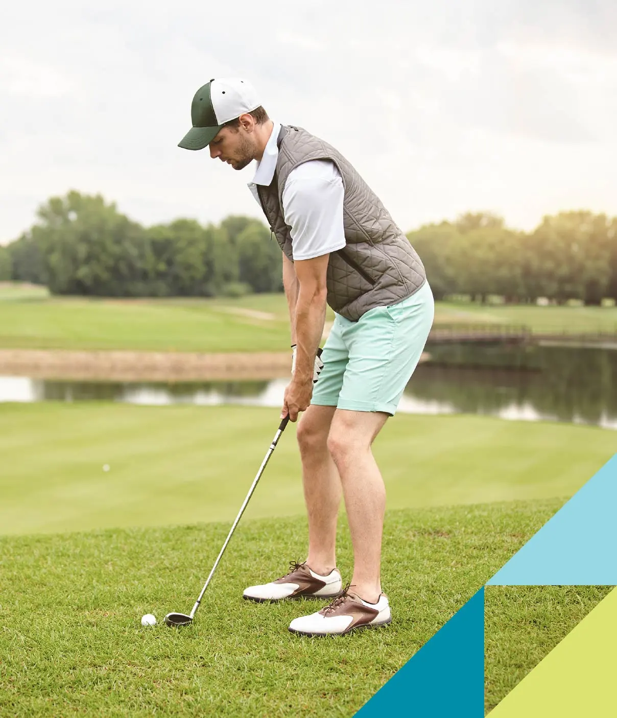 A man in golf attire prepares to chip from the putting green’s fringe.