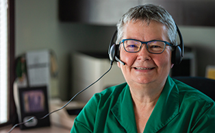  A female employee wearing a headset and green blouse smiles to camera. 